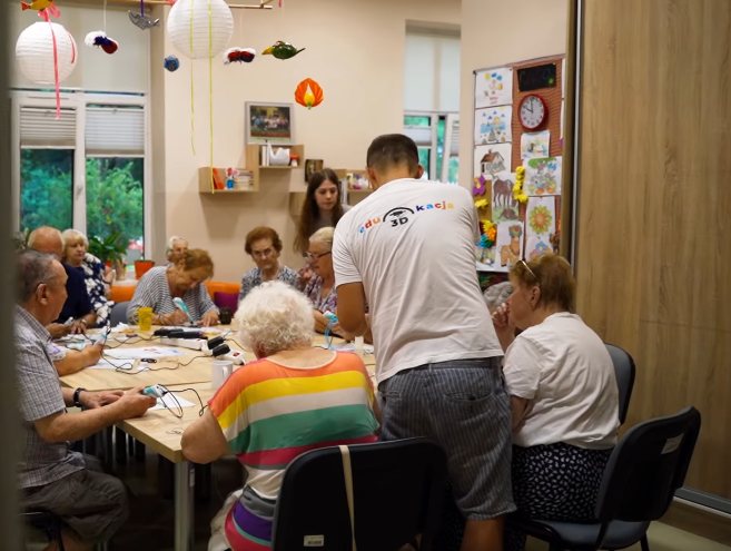 Instruktor pomaga seniorom podczas warsztatów