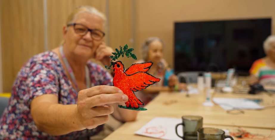 Seniorka pokazuje swoją pracę z długopisu 3D